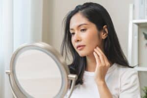 Woman looking in the mirror at her clear, acne-free skin after PCA peel in Chicago